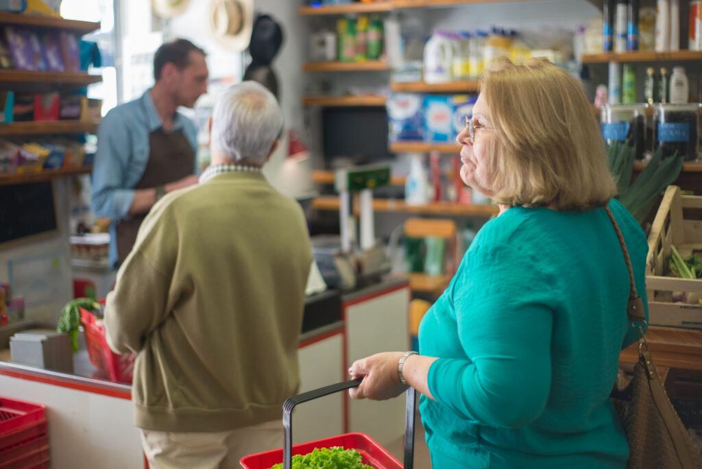 Image of an older woman standing in line at the grocery store